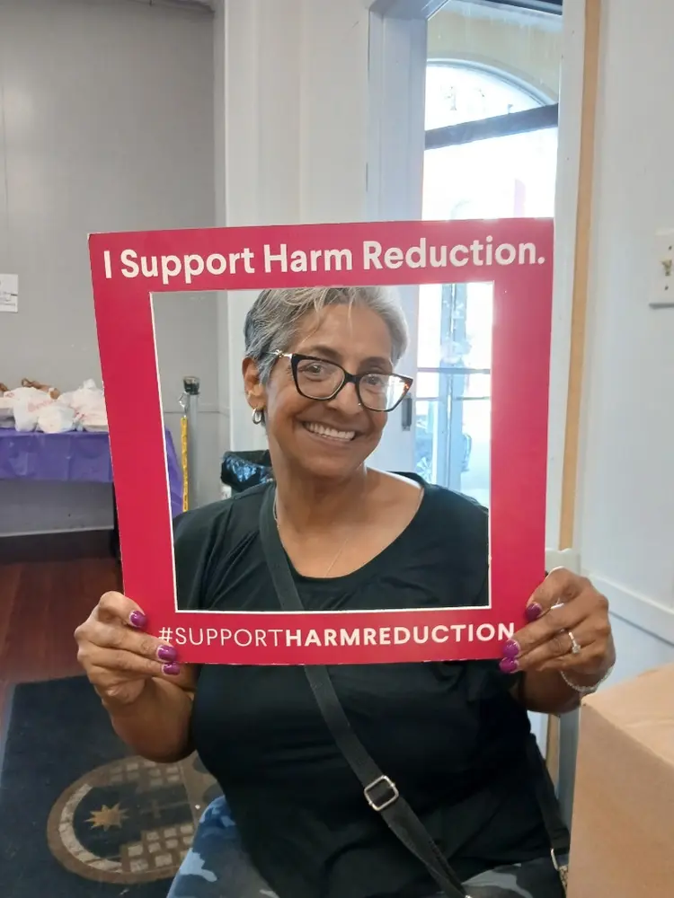 Emely Rolon holding an I Support Harm Reduction frame during community outreach